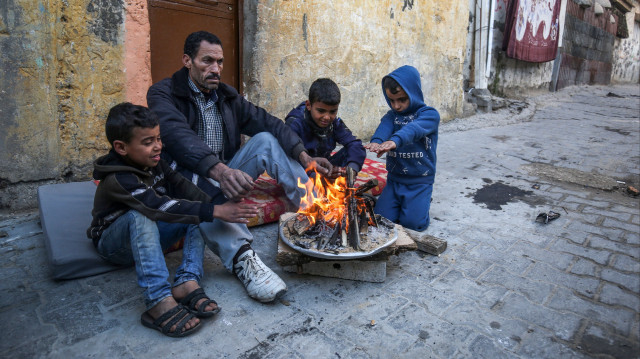 Des Palestiniens sont assis près d'un feu dans le camp de réfugiés de Khan Yunis, dans le sud de la bande de Gaza, le 28 janvier 2020.