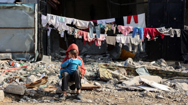 Des enfants palestiniens sont assis devant une ligne de linge suspendue le long d'un bâtiment endommagé dans le quartier de Shujaiya de la ville de Gaza, dans le nord de la bande de Gaza, le 4 janvier 2025.