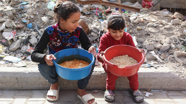 Des jeunes filles palestiniennes sont assises avec des bols de nourriture collectée à un point de don d'aide humanitaire, dans le camp d'al-Shati près de la ville de Gaza, le 26 décembre 2024, dans le cadre de la guerre en cours entre Israël et le mouvement palestinien Hamas.