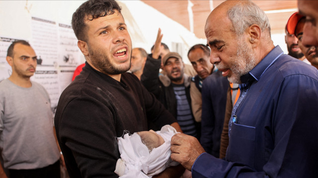 Des hommes réagissent devant le corps d'un bébé à l'hôpital arabe Al-Ahli, également connu sous le nom d'hôpital baptiste, dans la ville de Gaza, après qu'une maison a été touchée par un bombardement israélien au sud de la ville, le 12 novembre 2024, dans le cadre de la guerre en cours dans le territoire palestinien entre Israël et le Hamas.