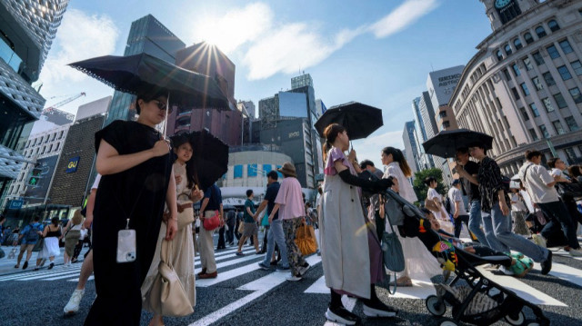 Des piétons marchent sur un passage piéton dans le centre de Tokyo où les températures ont dépassé les 35 degrés Celsius, le 8 juillet 2024. 