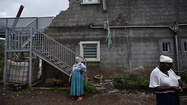 Des habitants dont les maisons ont été détruites par le cyclone Chido se tiennent devant un bâtiment endommagé dans le village de Sohoa, sur le territoire français de Mayotte dans l'océan Indien, le 6 janvier 2025.