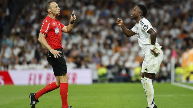 L'attaquant brésilien du Real Madrid Vinicius Junior s'entretient avec l'arbitre espagnol Guillermo Cuadra lors du match de championnat espagnol entre le Real Madrid CF et Villarreal CF au stade Santiago Bernabéu à Madrid, le 5 octobre 2024.