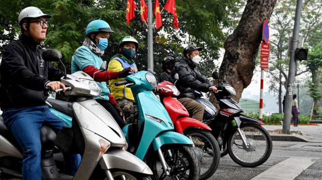 Des motocyclistes attendent à un feu rouge à un carrefour à Hanoi le 8 janvier 2025.