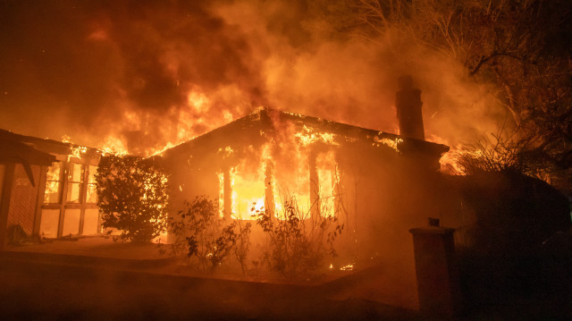 Les flammes de l'incendie de Palisades brûlent une maison lors d'une puissante tempête de vent le 8 janvier 2025 dans le quartier de Pacific Palisades à Los Angeles, en Californie.