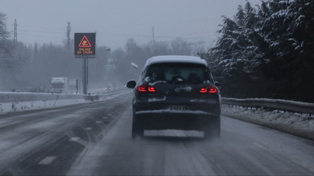 Une voiture roule sur l'autoroute A 26 entre Calais et Arras et passe sous un panneau annonçant le salage de l'autoroute suite aux chutes de neige de la nuit, le 9 janvier 2025.