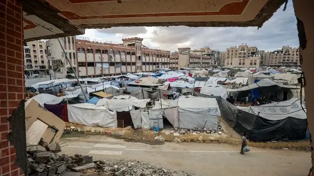 Un garçon passe devant des tentes abritant des personnes déplacées par la guerre près des bâtiments du complexe résidentiel Hamad City, construit par le Qatar, au nord-ouest de Khan Yunis, dans le sud de la bande de Gaza, le 6 octobre 2025.
