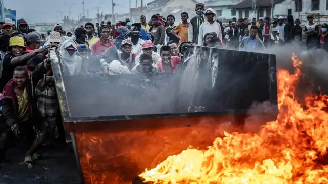 Des manifestants réagissent alors qu'ils poussent un conteneur métallique pour l'utiliser comme barricade lors d'affrontements avec les forces de sécurité malgaches, dans le cadre d'une grève appelant à des réformes constitutionnelles et à la démission du président Andry Rajoelina à Antananarivo, le 9 octobre 2025. 

