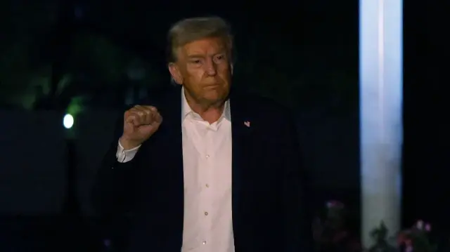 Le président américain Donald Trump lève le poing alors qu'il marche sur la pelouse sud après avoir atterri à la Maison Blanche le 14 octobre 2025 à Washington, DC. 
