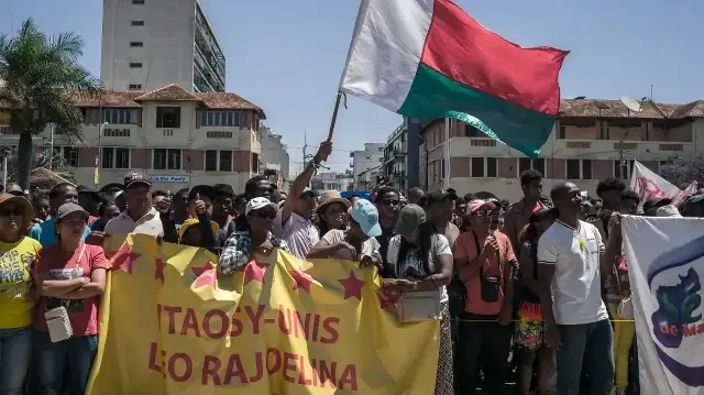 Des habitants et des manifestants brandissent des banderoles et un drapeau malgache et applaudissent lors d'un rassemblement de la société civile devant l'hôtel de ville d'Antananarivo, le 13 octobre 2025.
