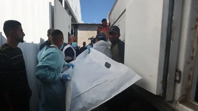 Des employés de la morgue déchargent les corps de Palestiniens qui étaient détenus par Israël, après avoir été transportés par des véhicules du Croissant-Rouge et des camions frigorifiques, à l'hôpital Nasser de Khan Yunis, dans le sud de la bande de Gaza, le 15 octobre 2025.