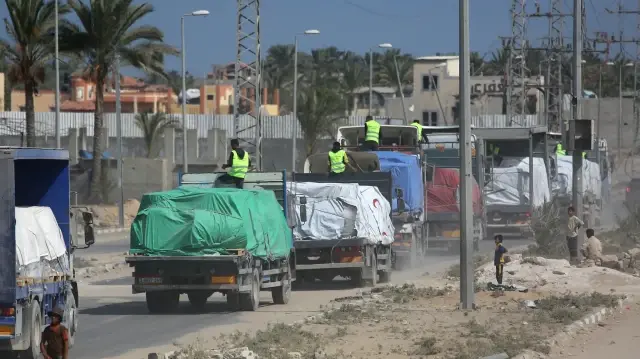 Des camions transportant l'aide fournie par le Programme alimentaire mondial (PAM) roulent sur une route à Deir el-Balah après avoir franchi le poste-frontière de Kerem Shalom, dans le sud de la bande de Gaza, le 17 octobre 2025.