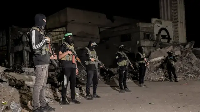 Des militants du Hamas montent la garde tandis que des véhicules du Comité international de la Croix-Rouge (non visibles sur la photo) transportent les corps des otages détenus à Gaza depuis l'attaque meurtrière du 7 octobre 2023, à Gaza, dans la bande de Gaza, le 15 octobre 2025. 
