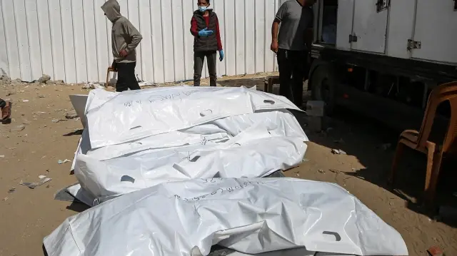 Des employés de la morgue déchargent les corps de Palestiniens détenus par Israël après leur transport par des véhicules du Croissant-Rouge et des camions frigorifiques à l'hôpital Nasser de Khan Yunis, dans la bande de Gaza, le 15 octobre 2025.