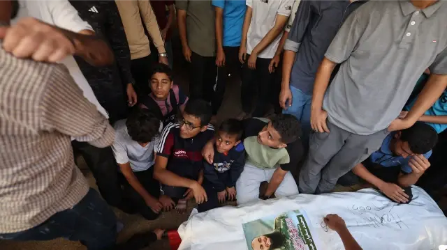 Des personnes en deuil entourent le corps d'un Palestinien libéré par Israël dans le cadre d'un cessez-le-feu à Gaza et d'un échange d'otages, avant ses funérailles dans le camp de réfugiés de Bureij, dans le centre de la bande de Gaza, le 18 octobre 2025. Israël a rendu les corps de 15 Palestiniens à Gaza le 18 octobre, portant à 135 le nombre total de corps remis, a déclaré le ministère de la Santé du territoire contrôlé par le Hamas.