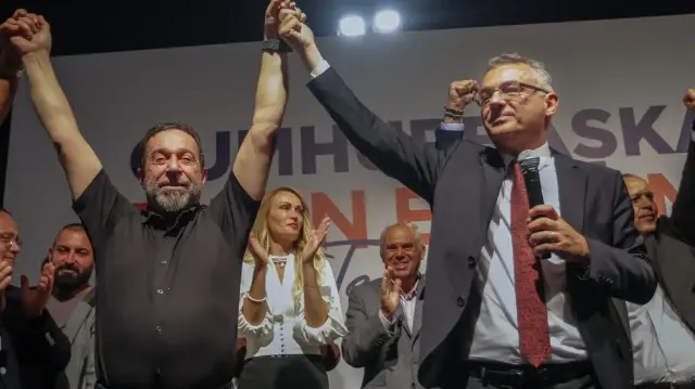Le chef du Parti républicain turc, Tufan Erhurman (à droite), célèbre avec d'autres dirigeants sur scène leur victoire aux élections présidentielles chypriotes turques dans la République turque de Chypre du Nord (RTCN), le 19 octobre 2025.