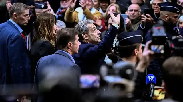 L'ancien président français Nicolas Sarkozy (au centre) salue ses partisans alors qu'il quitte sa résidence pour se présenter à la prison de La Santé afin d'y purger une peine de cinq ans d'emprisonnement après avoir été reconnu coupable de complot criminel dans le cadre d'un projet visant à financer sa campagne électorale de 2007 par le défunt dictateur libyen Mouammar Kadhafi, à Paris, le 21 octobre 2025.