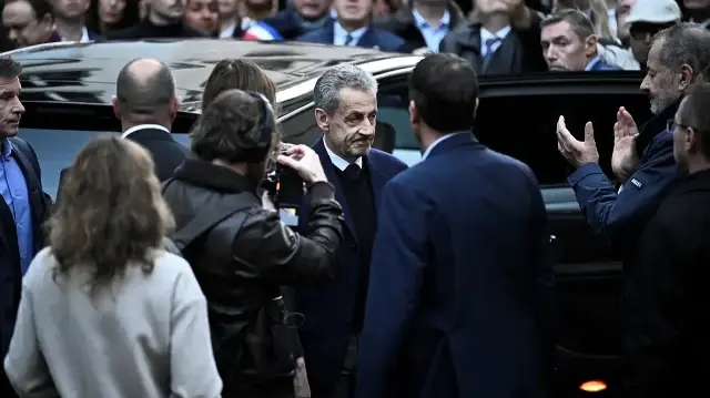 L'ancien président français Nicolas Sarkozy (au centre), entouré de ses partisans, quitte sa résidence pour se présenter à la prison de La Santé afin d'y purger une peine de cinq ans d'emprisonnement après avoir été condamné pour association de malfaiteurs dans le cadre d'un projet visant à financer sa campagne électorale de 2007 par le défunt dictateur libyen Mouammar Kadhafi, à Paris, le 21 octobre 2025.
