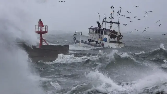 Un bateau de pêche arrive au port de Plobannalec-Lesconil, dans l'ouest de la France, le 22 octobre 2025, alors que d'énormes vagues et des vents violents frappent la côte lors du passage de la tempête Benjamin.