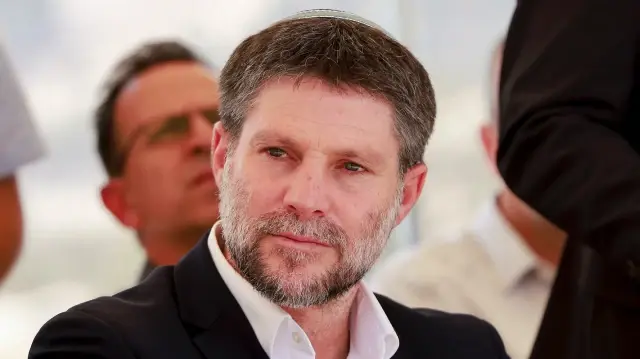 Le ministre israélien des Finances d'extrême droite, Bezalel Smotrich, assis avant une conférence de presse près de la colonie de Maale Adumim, dans un corridor terrestre connu sous le nom de E1, à l'extérieur de Jérusalem, en Palestine occupée, le 14 août 2025. 