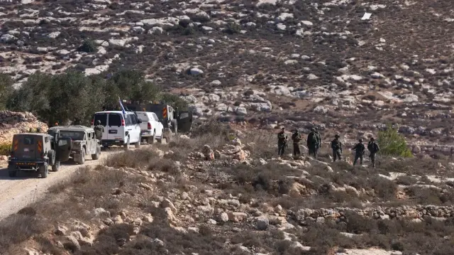 Des soldats israéliens prennent position alors que des Palestiniens récoltent des olives dans le village occupé de Turmus Ayya, en Palestine occupée, à la périphérie de Ramallah, le 20 octobre 2025.