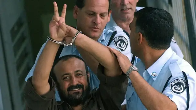 مروان برغوثی کی 2003 کی ایک تصویر جس میں انہیں تل ابیب کی عدالت میں پیشی کے بعد پولیس کی گاڑی کی طرف لے جایا جا رہا ہے۔ (اے ایف پی)
