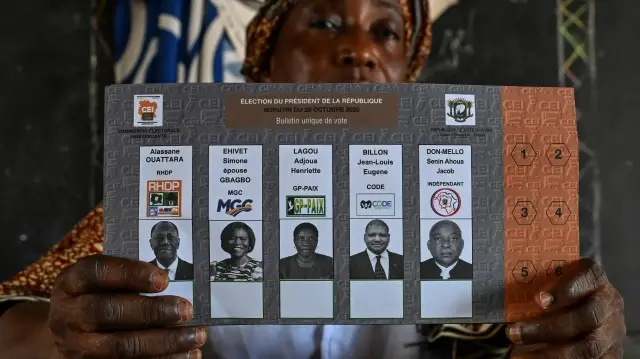 Un responsable de la Commission électorale indépendante de Côte d'Ivoire (CEI) enregistre les données biométriques d'un électeur dans un bureau de vote à Agboville, le 25 octobre 2025, lors de l'élection présidentielle ivoirienne.