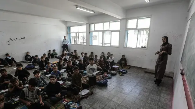 Des élèves palestiniens assistent à des cours dans une salle de classe où ils sont assis par terre à l'école Al-Razi après la reprise des cours dans les écoles de l'Office de secours et de travaux des Nations Unies pour les réfugiés de Palestine dans le Proche-Orient (UNRWA) à Gaza, le 26 octobre 2025. Les écoles de l'UNRWA, qui ont servi de refuges pour les familles déplacées depuis longtemps, accueillent à nouveau des élèves après près de deux ans de guerre et de déplacements.