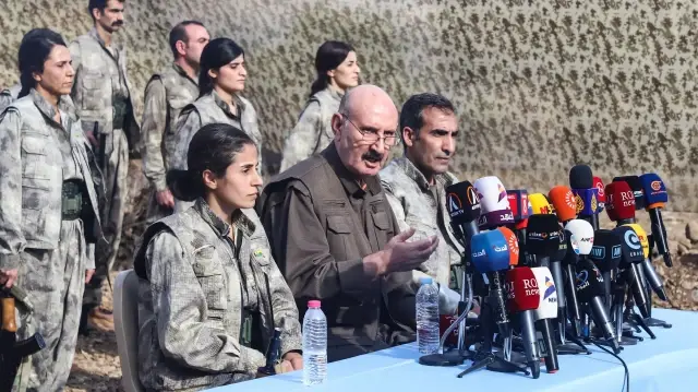 Sabri Ok (au centre), haut responsable du Parti des travailleurs du Kurdistan (PKK), s'adresse aux journalistes lors d'une cérémonie dans la région de Qandil, dans le nord de l'Irak, où le groupe militant a annoncé le retrait complet de ses forces de Türkiye, le 26 octobre 2025.