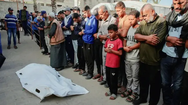 Des Palestiniens récitent des prières funéraires près des corps des personnes tuées lors d'une attaque israélienne à Khan Yunis, dans le sud de la bande de Gaza, le 20 octobre 2025.