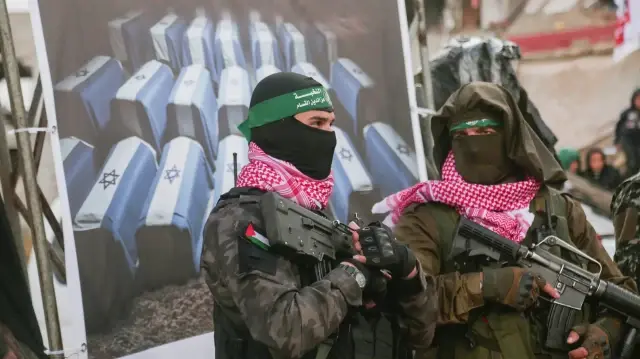 Deux combattants palestiniens du Hamas montent la garde alors que des véhicules de la Croix-Rouge arrivent sur le site de la remise des corps de quatre otages israéliens à Khan Yunis, dans le sud de Gaza, le 20 février 2025.