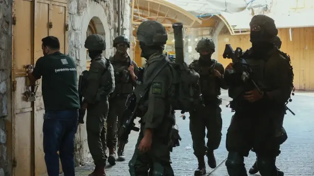 Des soldats israéliens patrouillent dans les rues de la vieille ville d'Hébron, en Cisjordanie occupée, le 25 octobre 2025, tandis que des colons visitent la région sous la protection de l'armée.