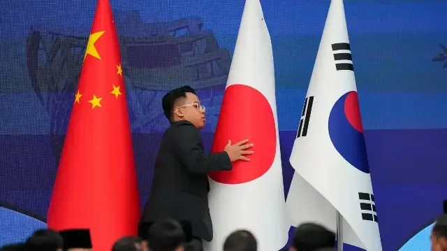 Un membre du personnel organise les drapeaux nationaux de la Chine, du Japon et de la Corée du Sud avant le début du 28e sommet ASEAN Plus Trois (APT) lors du 47e sommet de l'Association des nations de l'Asie du Sud-Est (ASEAN) à Kuala Lumpur, le 27 octobre 2025.