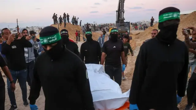 Des gens regardent des militants du Hamas transporter un corps retrouvé dans un tunnel au nord de Khan Yunis, dans le sud de la bande de Gaza, le 28 octobre 2025. Le 28 octobre, l'armée israélienne a accusé le Hamas d'avoir mis en scène la recherche du corps d'un otage à Gaza, l'un des 28 que le groupe avait accepté de remettre dans le cadre d'un accord de cessez-le-feu. Le Hamas affirme qu'il respecte les termes du cessez-le-feu, mais qu'il ne dispose pas de l'équipement nécessaire pour localiser et exhumer les corps des otages potentiellement ensevelis sous des bâtiments effondrés par des frappes aériennes. 