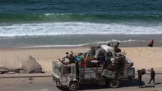 Des Palestiniens transportent leurs affaires le long d’un sentier côtier au nord-ouest du camp de réfugiés de Nuseirat, alors qu’ils se déplacent vers le sud depuis Wadi Gaza après l’annonce israélienne de la fermeture de la route Al-Rashid en direction du nord de la bande de Gaza assiégée, le 2 octobre 2025.