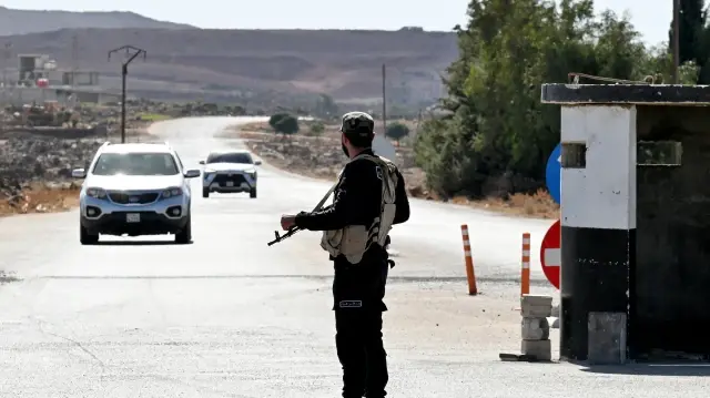 Un membre des forces de sécurité syriennes monte la garde devant une ancienne base militaire près de la ville de Quneitra, dans le sud de la Syrie, à la lisière du plateau du Golan annexé par Israël, le 21 septembre 2025.