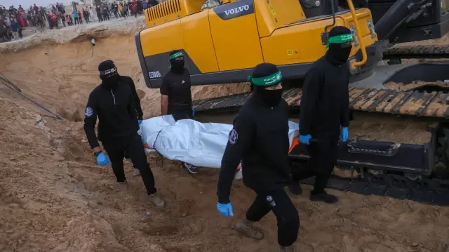 Des personnes regardent des militants du Hamas transporter un corps retrouvé dans un tunnel au nord de Khan Yunis, dans le sud de la bande de Gaza, le 28 octobre 2025.