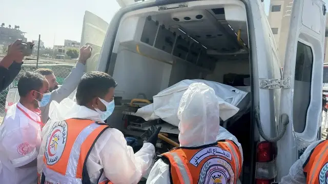 Les équipes de la défense civile et des services de santé chargent le corps d'un Palestinien non identifié dans une ambulance à Khan Younes, dans la bande de Gaza, le 22 octobre 2025.