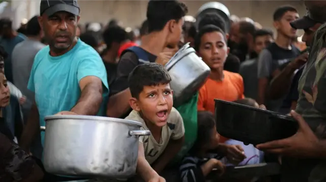 Des enfants palestiniens se rassemblent pour recevoir des portions alimentaires distribuées par une cuisine caritative à Nuseirat, dans le centre de la bande de Gaza, le 30 septembre 2025.