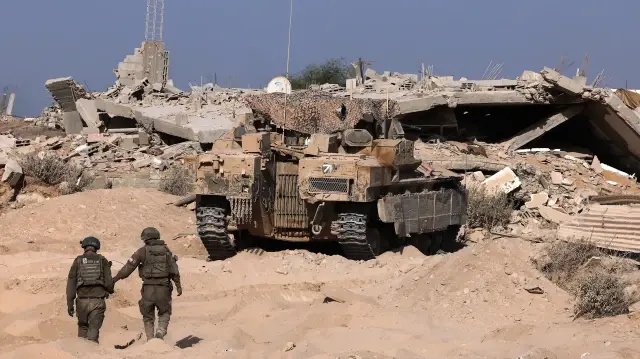 Cette photo prise lors d'une visite organisée par l'armée israélienne le 3 octobre 2025 montre des soldats de l'armée israélienne marchant vers un char d'assaut près de l'hôpital de campagne jordanien à Gaza. 