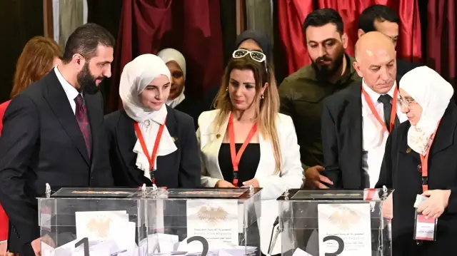 Le président par intérim syrien Ahmed al-Sharaa (à gauche) visite le bureau de vote où les membres des comités locaux syriens ont voté dans le cadre du processus de sélection visant à désigner un parlement provisoire, à Damas, le 5 octobre 2025. 
