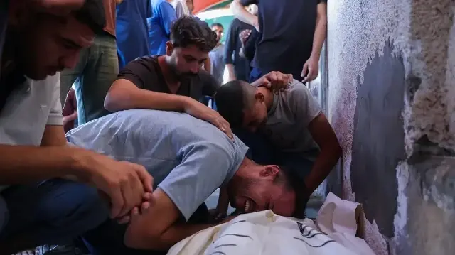 Des Palestiniens pleurent près du corps d'un proche tué lors de frappes israéliennes à Deir al-Balah, à l'hôpital Al-Aqsa Martyrs, dans le centre de la bande de Gaza, le 2 octobre 2025.
