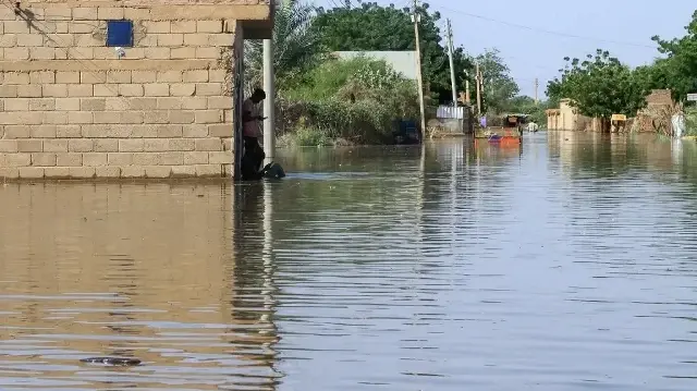 Un habitant se tient devant un bâtiment entouré d'eau qui recouvre une route en raison de la crue du Nil dans le village soudanais de Wad Ramli, au nord de Khartoum, le 1er octobre 2025.