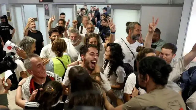 Des militants espagnols (chemises blanches) qui naviguaient à bord des navires de la flottille Global Sumud célèbrent leur arrivée à l'aéroport de Madrid-Barajas le 5 octobre 2025, après qu'Israël ait intercepté la flottille d'aide humanitaire à destination de Gaza et arrêté des centaines de personnes.