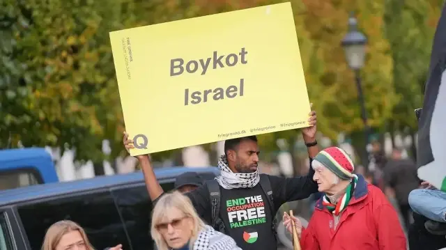 Un manifestant portant un t-shirt avec l'inscription « Fin de l'occupation - Palestine libre » brandit une pancarte sur laquelle on peut lire « Boycottons Israël » lors d'une manifestation en marge d'une réunion informelle des chefs d'État et de gouvernement de l'UE à Copenhague, le 1er octobre 2025.
