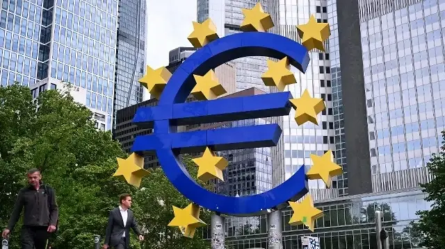 Des piétons passent devant la "sculpture de l'euro" de l'artiste allemand Ottmar Hörl, située devant l'ancien siège de la Banque centrale européenne (BCE) à l'Eurotower, avant une conférence de presse sur la politique monétaire de la zone euro, à Francfort-sur-le-Main, dans l'ouest de l'Allemagne, le 5 juin 2025.