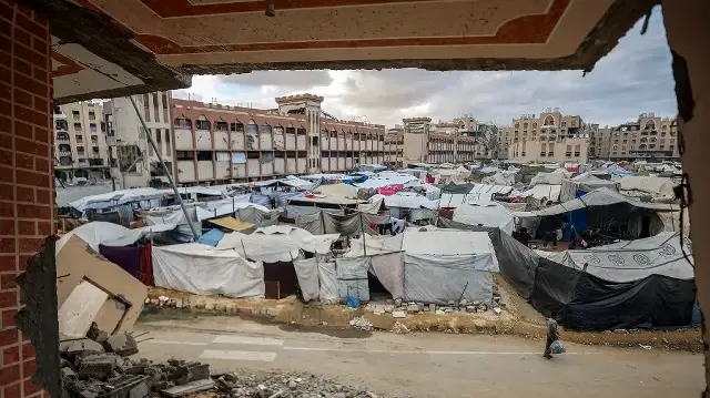 Un garçon passe devant des tentes abritant des personnes déplacées par la guerre près des bâtiments du complexe résidentiel Hamad City, construit par le Qatar, au nord-ouest de Khan Yunis, dans le sud de la bande de Gaza, le 6 octobre 2025.