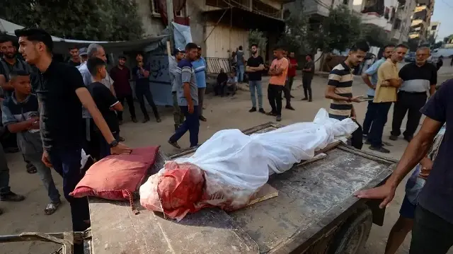 Des Palestiniens transportent le corps d'un homme tué lors d'un bombardement israélien à l'hôpital al-Awda dans le camp de réfugiés de Nuseirat, dans le centre de la bande de Gaza, le 28 septembre 2025.