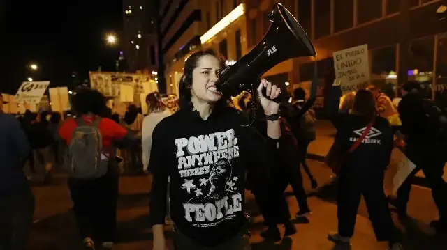 Des personnes scandent des slogans pour protester contre l'arrivée de la Garde nationale du Texas et des agents de l'agence américaine de contrôle de l'immigration et des douanes dans le centre-ville de Chicago, dans l'Illinois, le 8 octobre 2025.