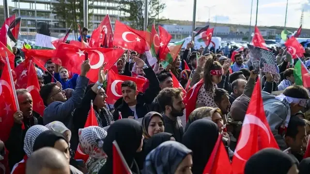 Des personnes agitent des drapeaux turcs en attendant l'arrivée de trente-six Turcs et ressortissants de 12 pays qui devaient arriver à l'aéroport d'Istanbul à bord d'un vol spécial après qu'Israël ait intercepté une flottille d'aide humanitaire à destination de Gaza et arrêté des centaines de personnes, à Istanbul, le 4 octobre 2025. 
